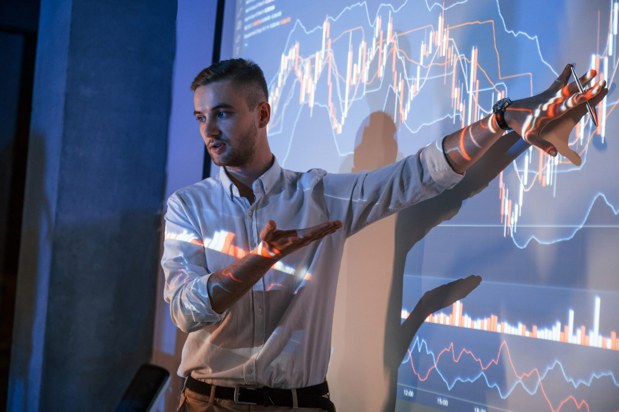 Man is standing near projector and showing graphs and business graphs